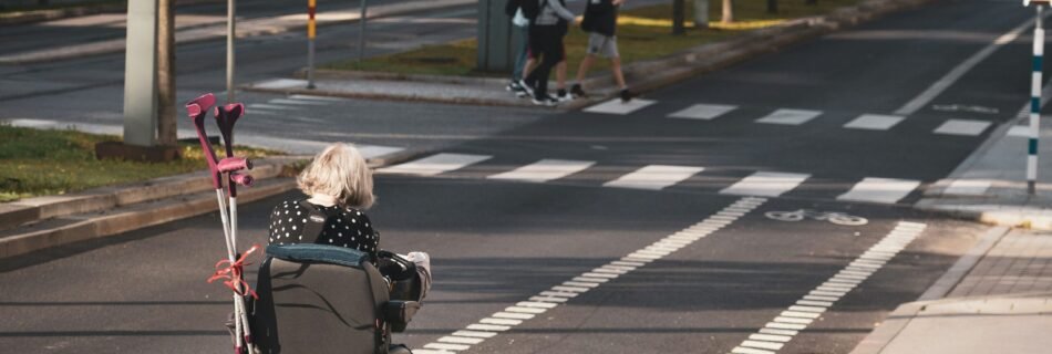 girl in black jacket riding on black and gray stroller on gray asphalt road during daytime