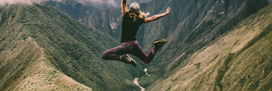 woman jumping on green mountains