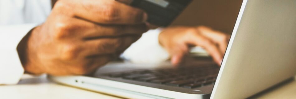 person using laptop computer holding card